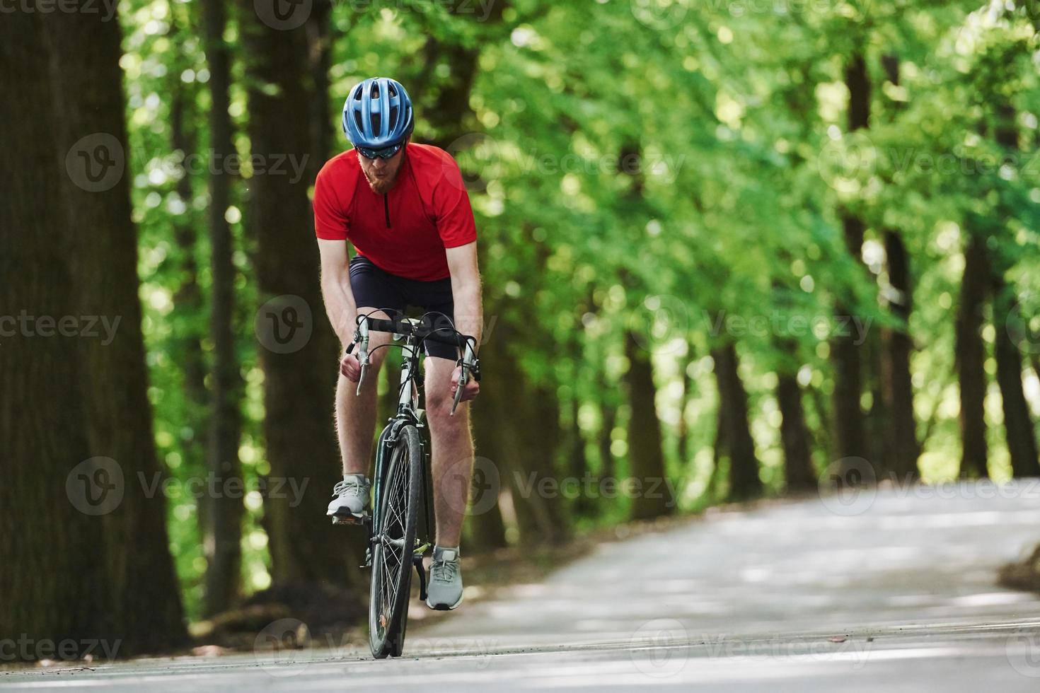 fritidsaktiviteter. cyklist på en cykel är på asfaltvägen i skogen på en solig dag foto