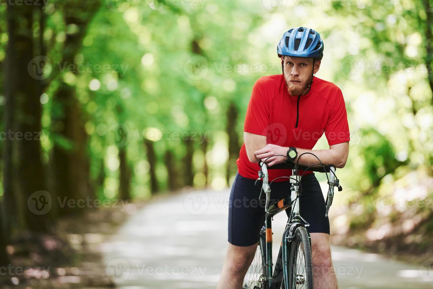 seriös man. cyklist på en cykel är på asfaltvägen i skogen på en solig dag foto