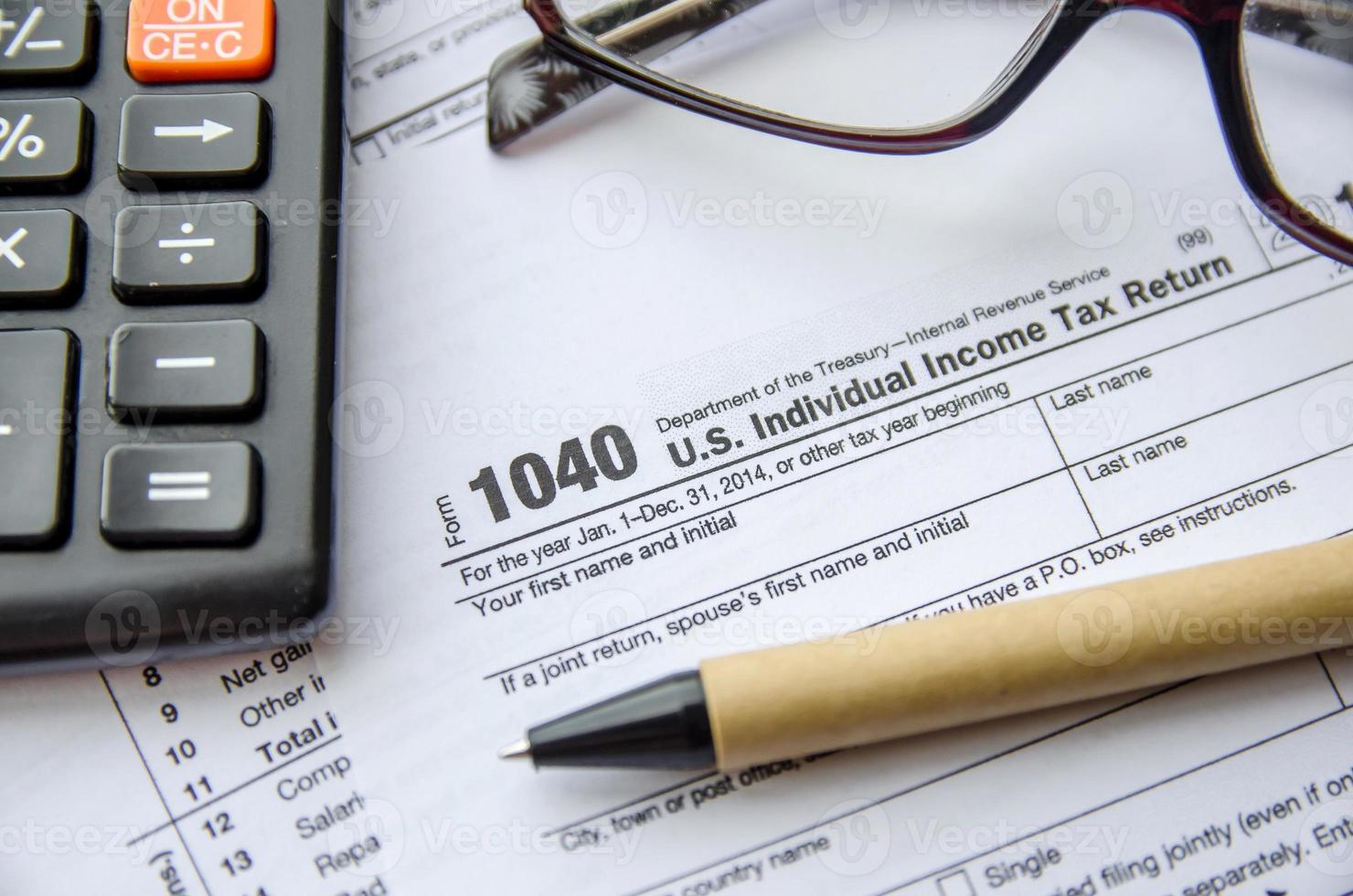 individuell inkomstdeklarationsformulär, glasögon, penna och miniräknare foto