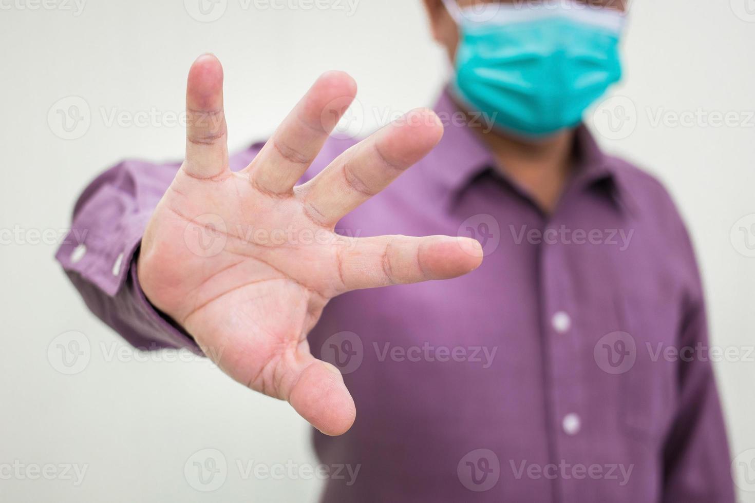 manlig hand gör stopp covid tecken gest medan han bär en medicinsk ansiktsmask foto