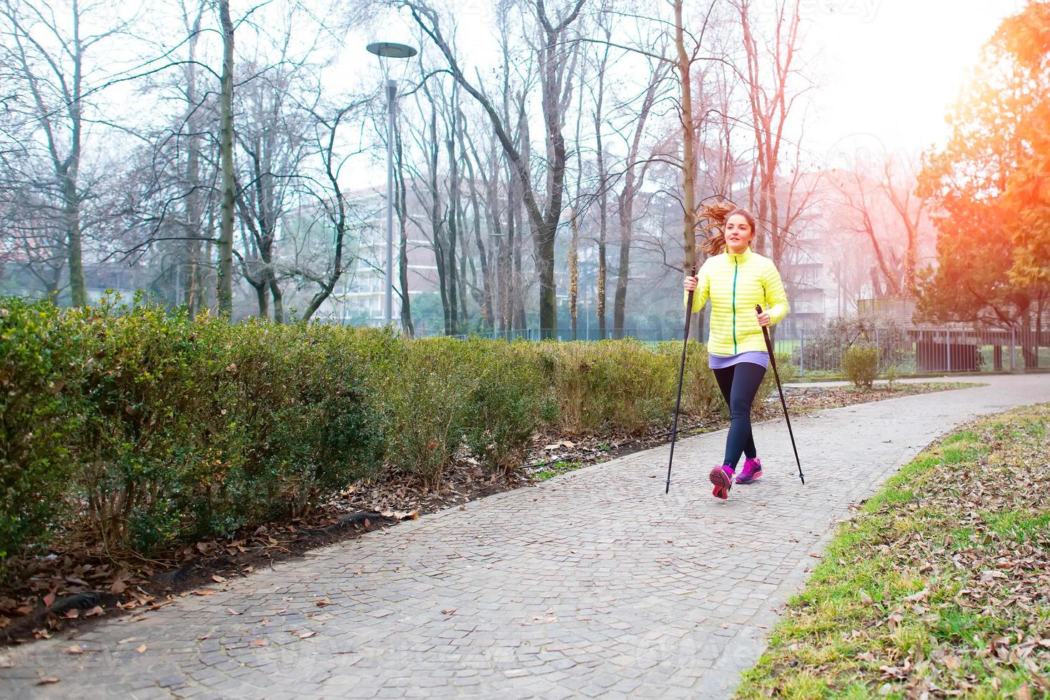 flicka göra stavgång i parken i staden foto