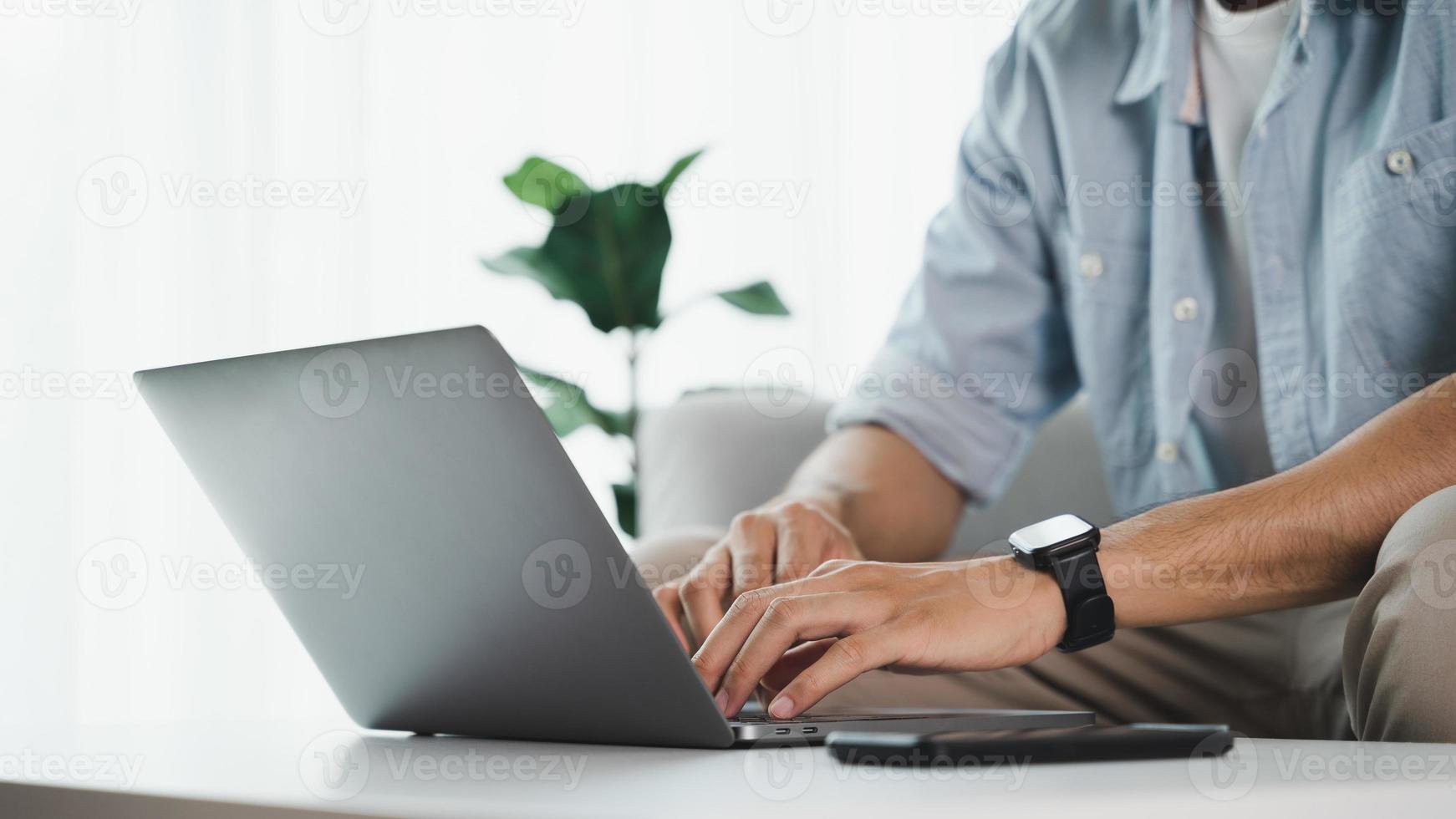 närbild av man händer att skriva på laptop tangentbord på bordet på hemmakontoret eller arbetsplatsen. foto
