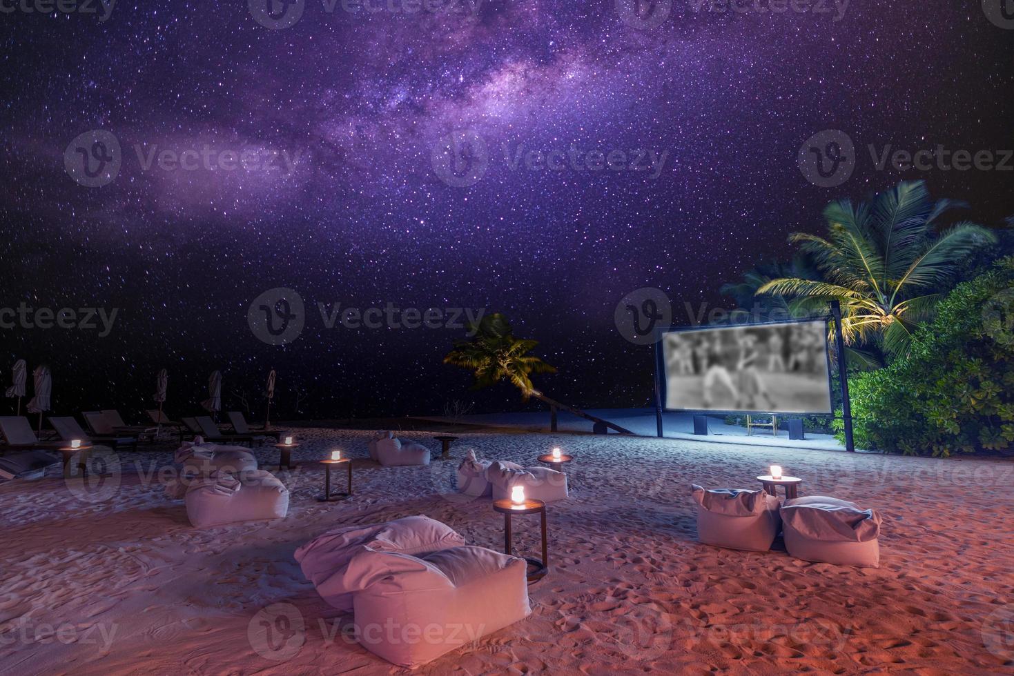 filmkväll på stjärnklar tropisk ö-strand. otroligt lugn och avslappnad naturskön utsikt över utomhusbio med Vintergatan och palmer med mjukt levande ljus. sommar familjesemester, lyxig livsstil foto