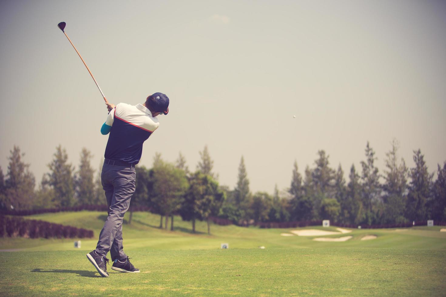 golfare slår svepande golfbana på sommaren. vintage färg foto