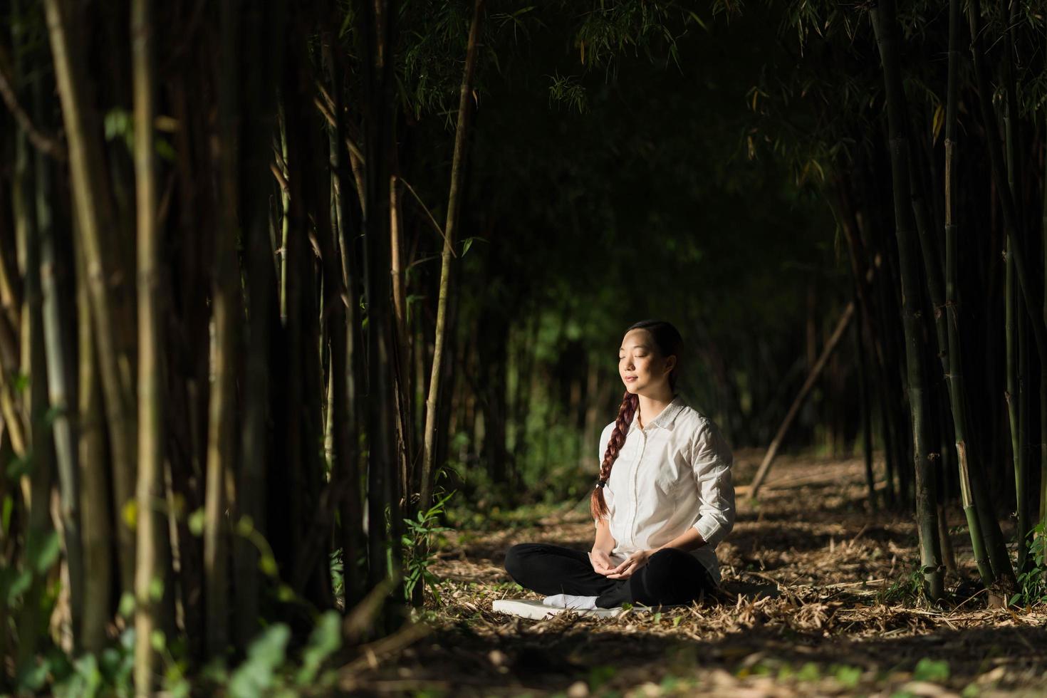 porträtt vacker kvinna mediterar i bambuskog foto