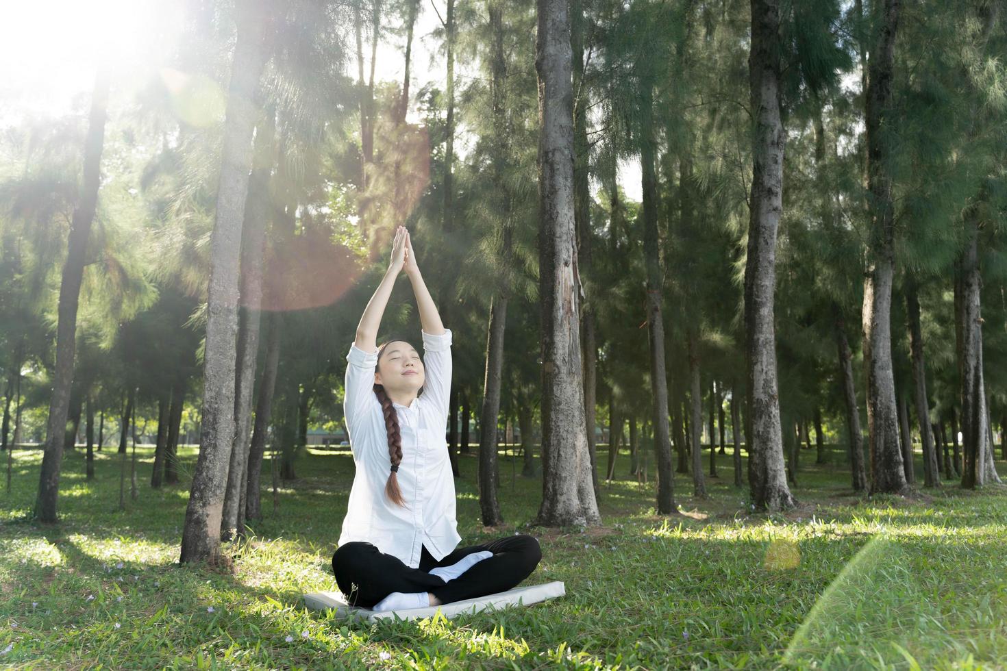 flicka gör yogaställning i parken på morgonen med solljus. foto