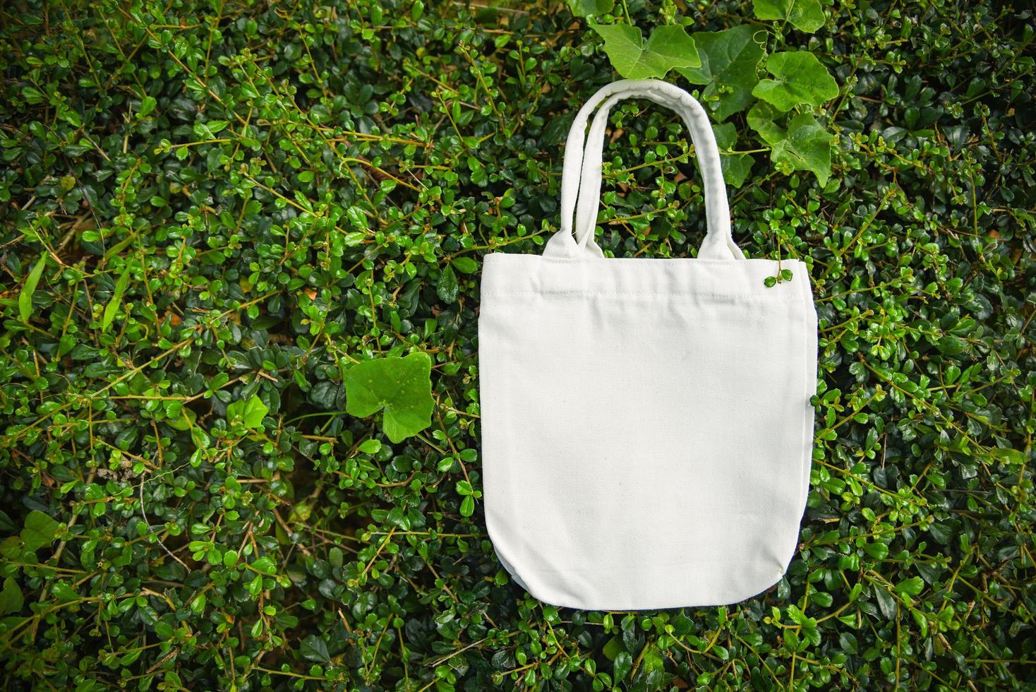 vit tote canvas tyg eco bag tyg shoppingsäck på gröna blad natur bakgrund foto