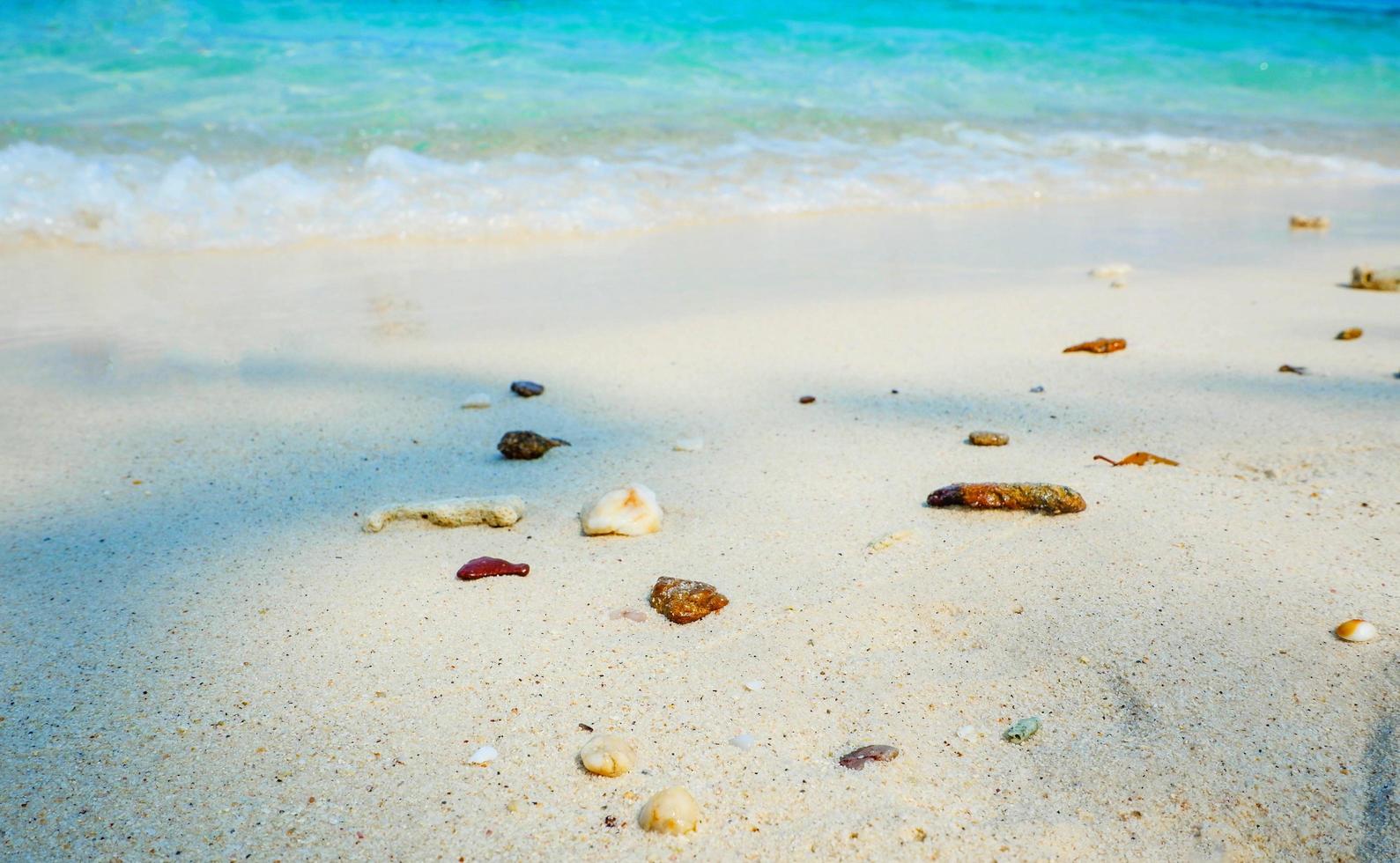 vacker strand och blått hav på stranden med sten på sandön naturligt hav foto