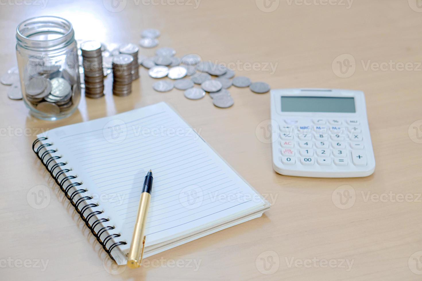 kontorsanteckningsbok, miniräknare, mynt och penna foto