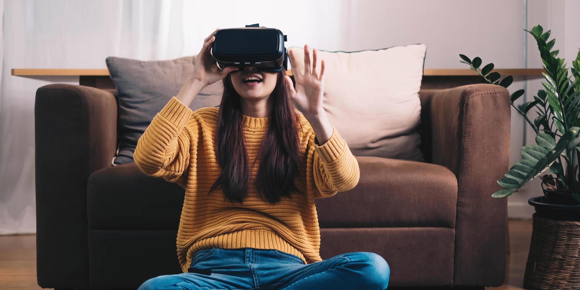 asiatisk kvinna spelar vr-spel för att underhålla hemma, asiatisk kvinna glad i huset på semestern. glad kvinna spelar metaverse vr teknologikoncept. foto