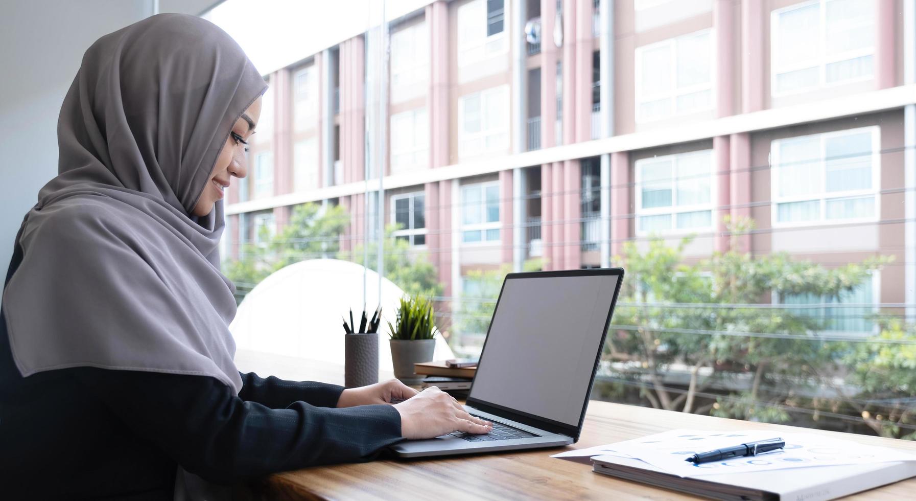 glad arabisk kvinna frilansare chattar med kunder på laptop, sitter på café, tomt utrymme foto