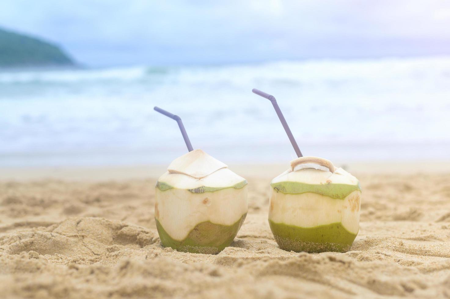 färsk kokosnöt med sugrör på stranden, resor och semester koncept. foto