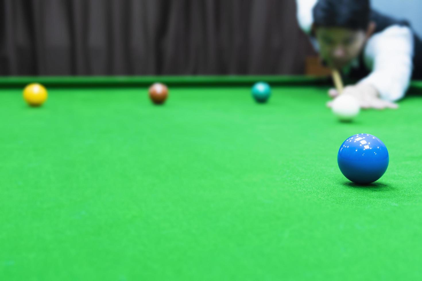 asiatisk man som spelar snooker som riktar sin köpinne mot en vit köboll - snookerspelare i tävlingsmatchkoncept foto