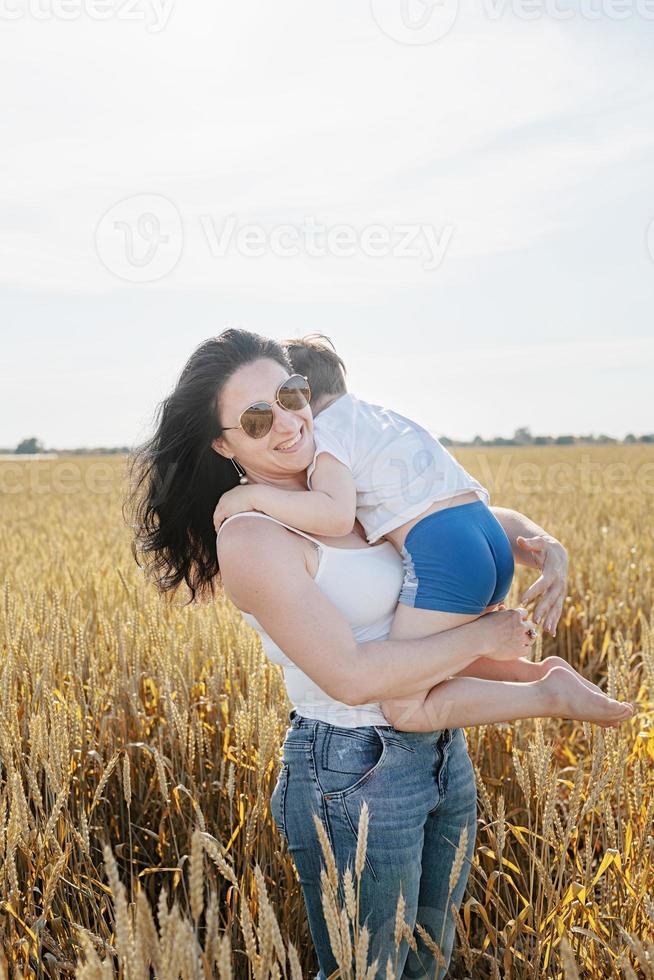 lycklig familj av mor och spädbarn barn går på vetefält foto