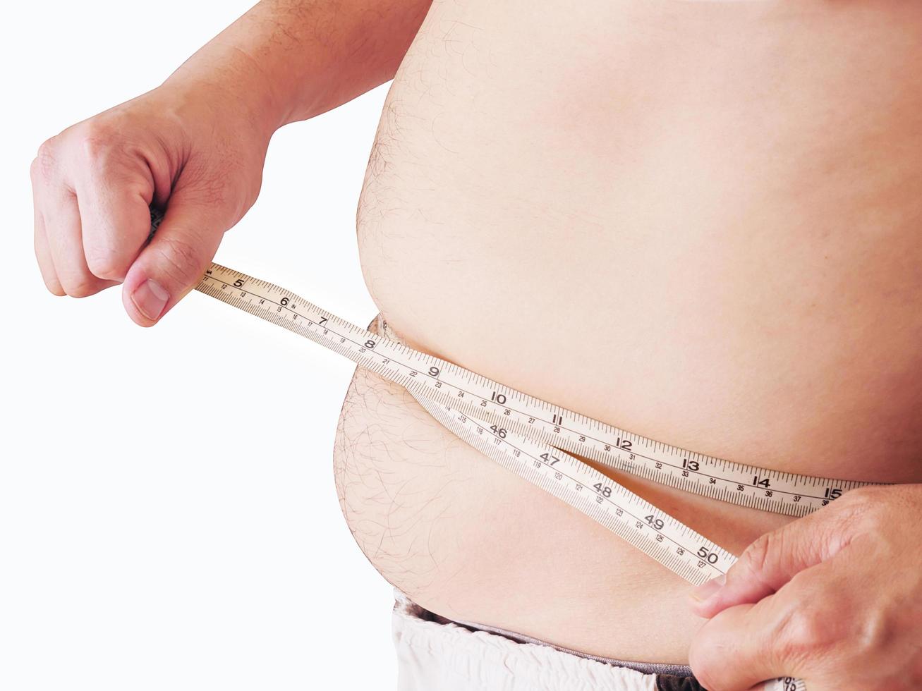 fet man mäter sin mage med hjälp av bandmätare - kosthälsokoncept foto