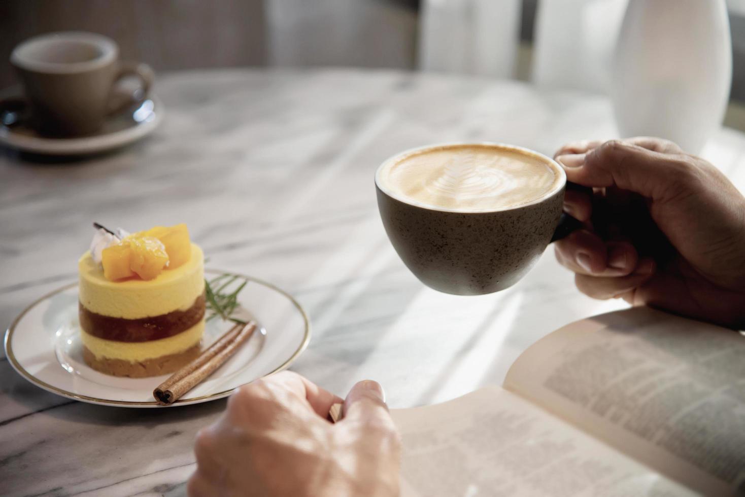 slappna av asiatisk man dricker kaffe och läser bok i ett kafé i modern stil - människor med kaffekopp enkelt livsstilskoncept foto