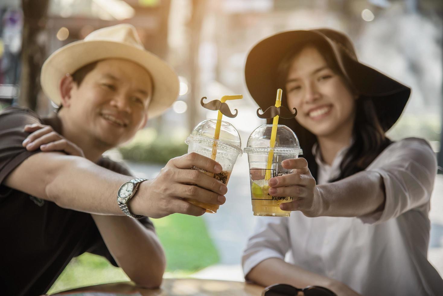Asiatiska par tycker om att resa sittande på kaféet - glada unga människor på semester koncept foto