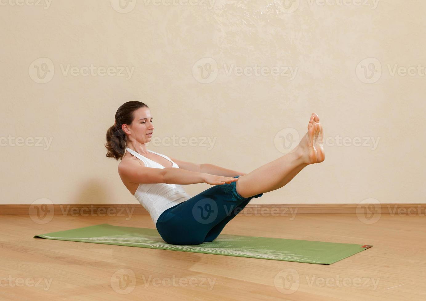 kaukasisk kvinna utövar yoga i studion (paripurna navasana foto