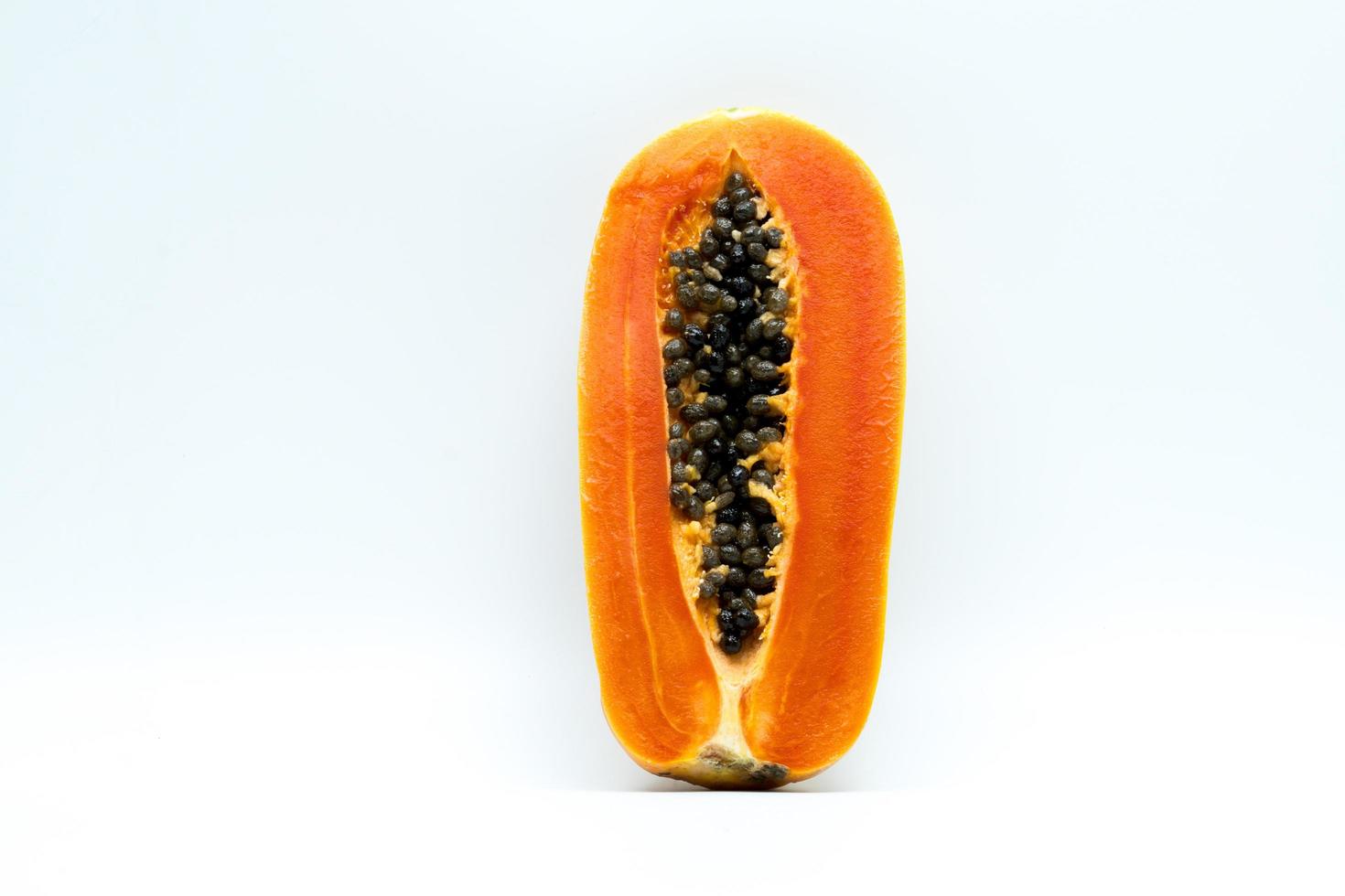 hälften av mogen papaya frukt med frön isolerad på vit bakgrund med kopia utrymme. naturlig källa till vitamin c, folat och mineraler. hälsosam mat för gravida och ammande kvinnor foto