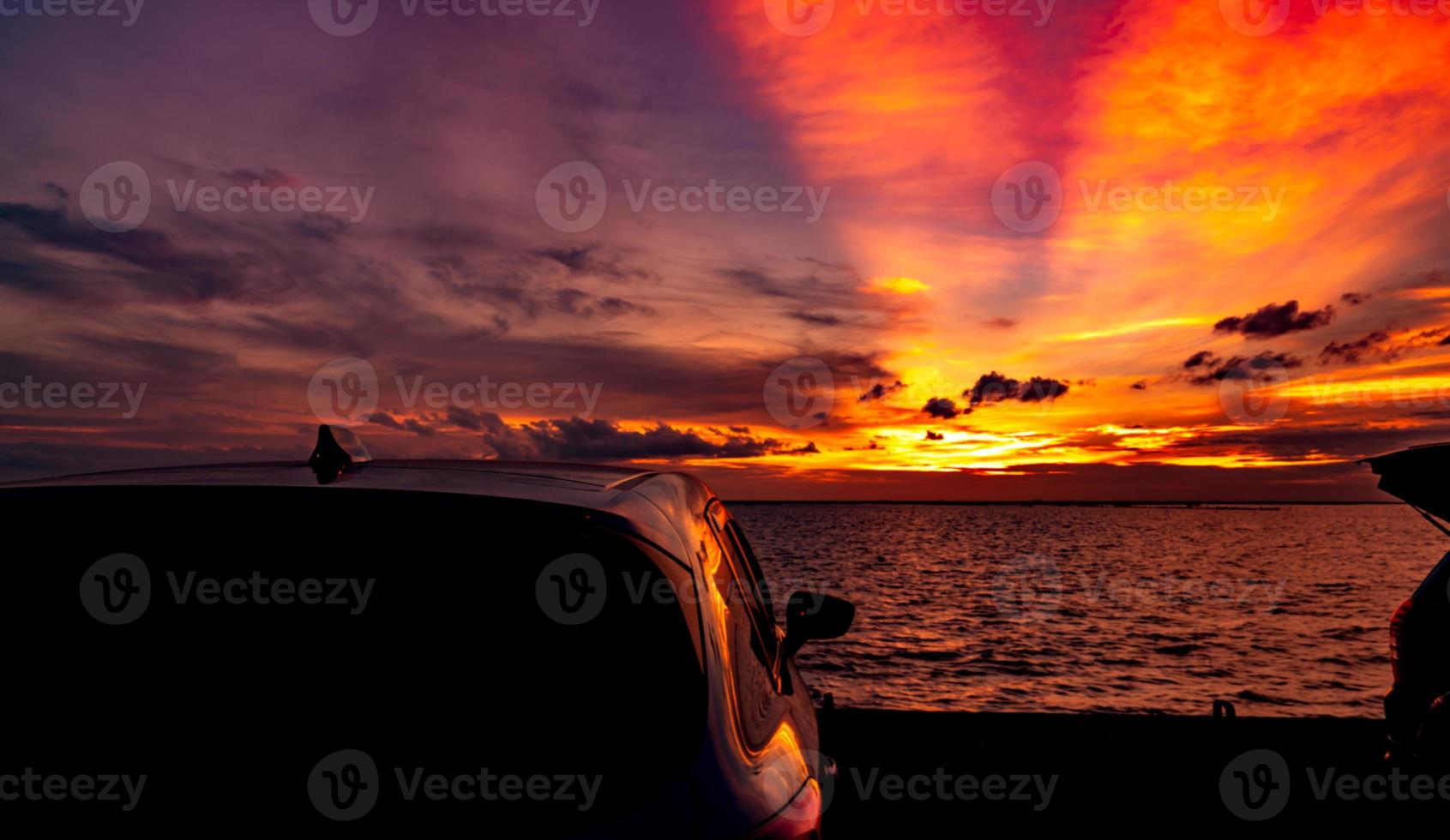 siluett suv bil med sport och modern design parkerad på betongväg vid havet i solnedgången. roadtrip resor på semester på stranden och öppen bil lastbil med vacker orange solnedgång himmel och moln. foto