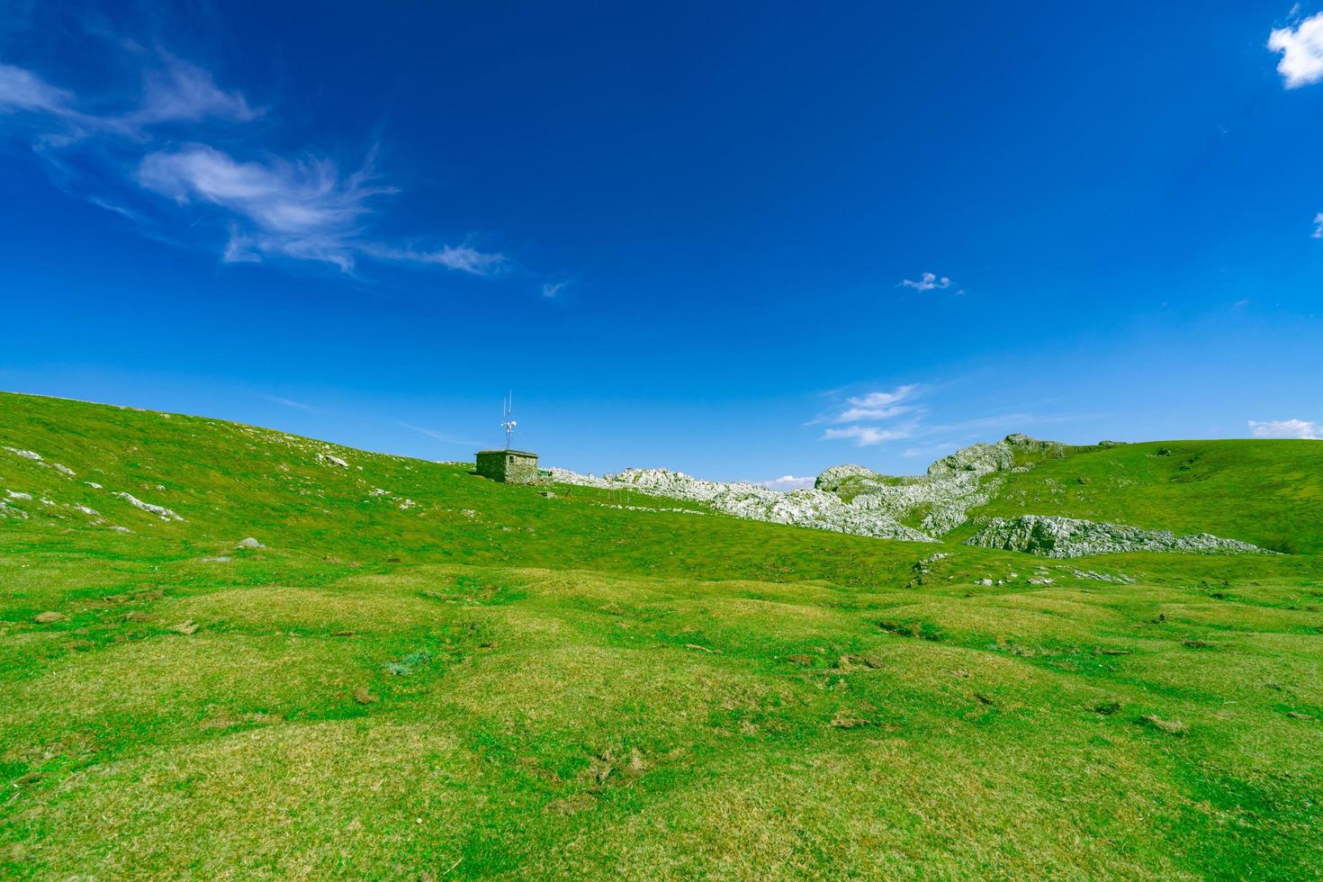 landskap av grönt gräs och rock hill på våren med vacker blå himmel och vita moln. utsikt över landsbygden eller landsbygden. natur bakgrund i solig dag. frisk luft miljö. sten på berget. foto