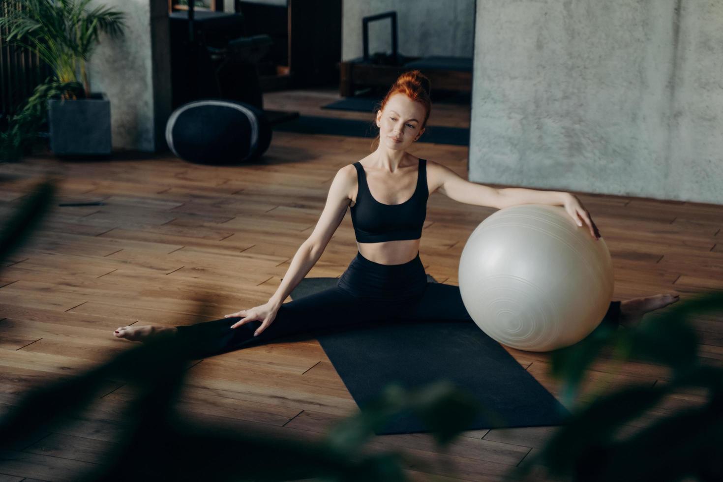 sportig kvinna avkopplande under pilatesträning med träningsboll foto