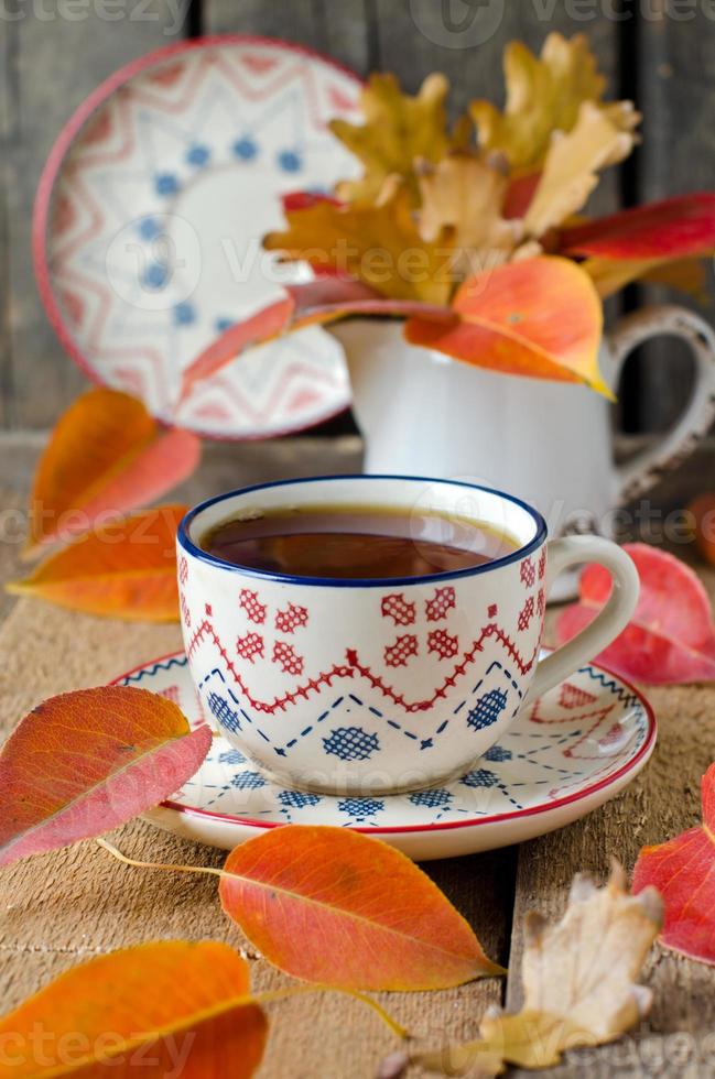 kopp te på bordet med höstlöv foto