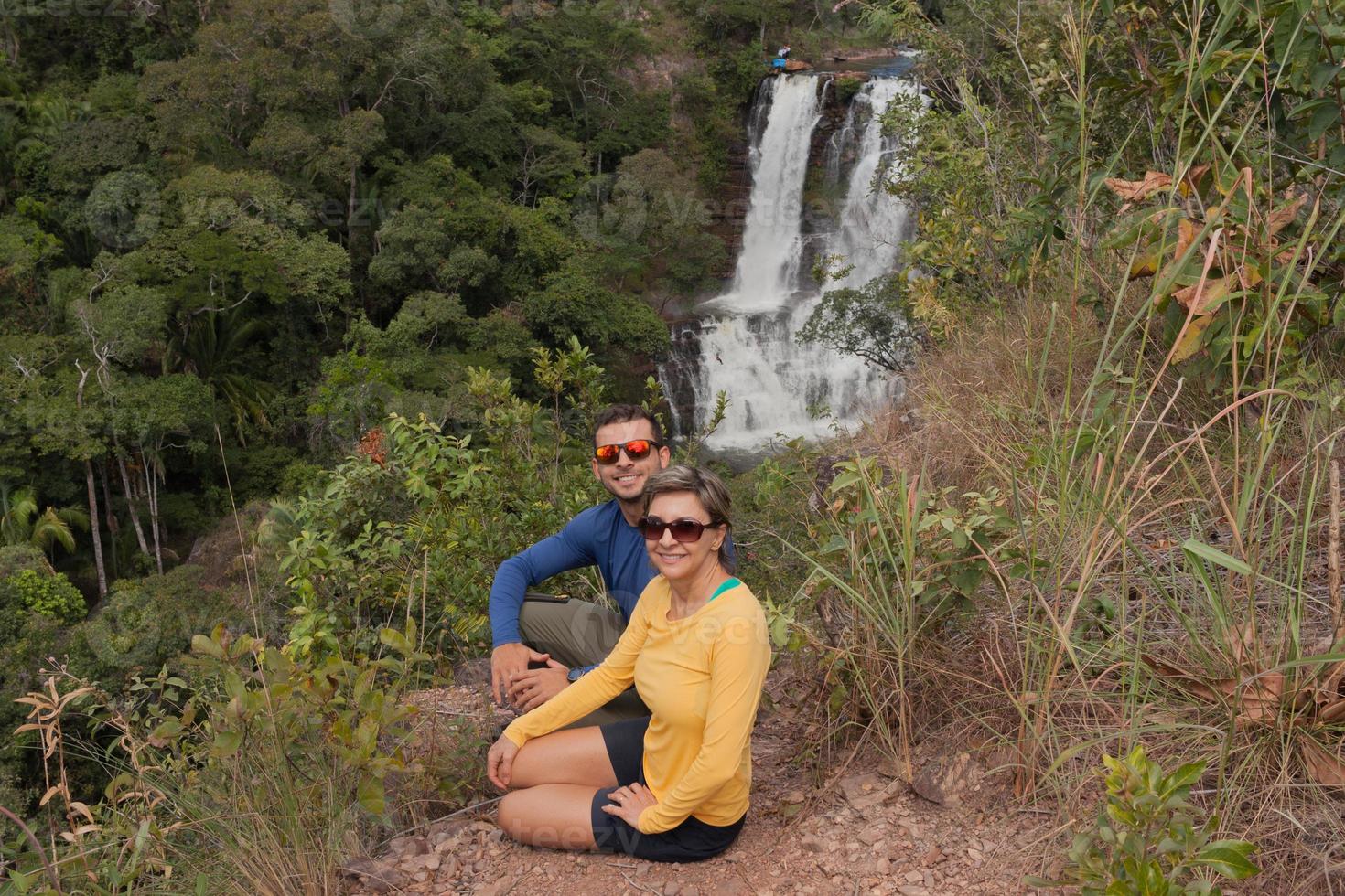 par sitter med utsikt över vattenfallet veu de noiva längs leden i indaia nära formosa, goias, brasilien foto