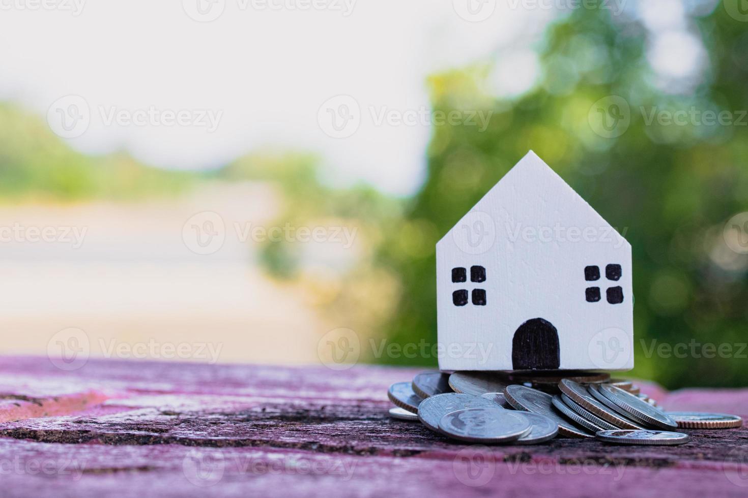 vitt hus med högar av mynt. pengar att spara idéer för fastigheter. foto