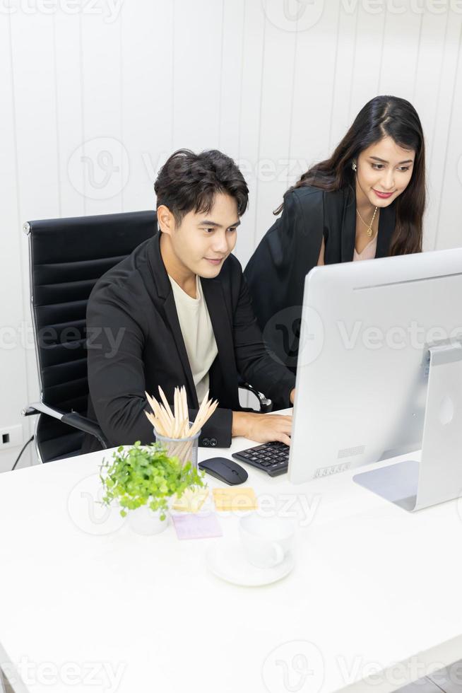 president och sekreterare använder dator för att arbeta och diskutera tillsammans på kontoret. affärsman och affärskvinna pratar och ser dator på kontoret. foto