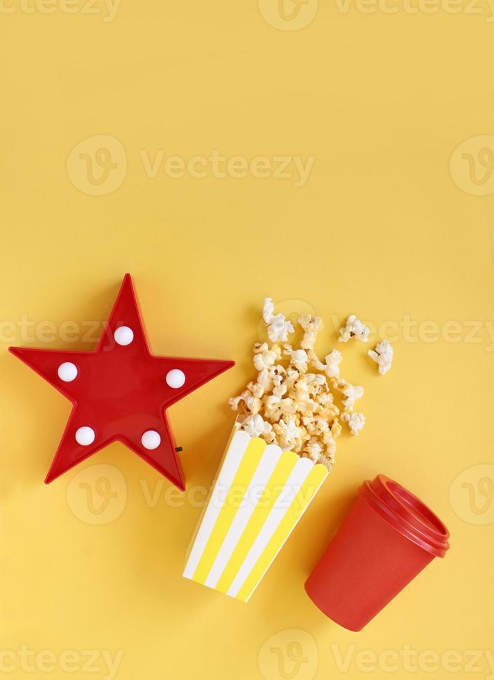 spilld popcorn och pappershink på bakgrunden. filmkväll koncept. kopiera utrymme för text foto