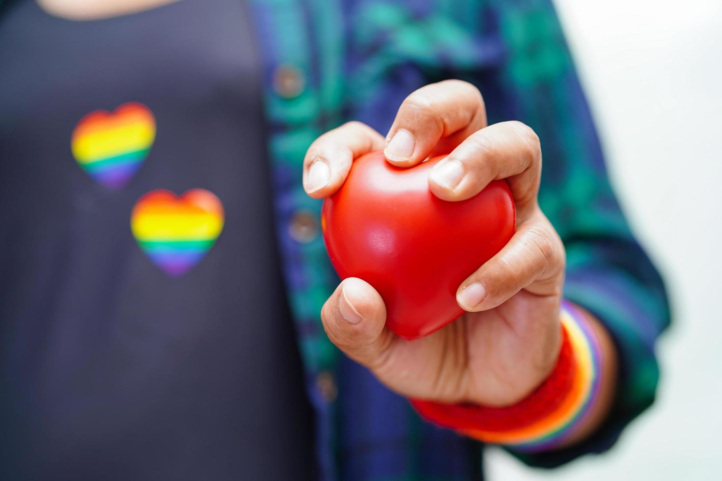 asiatisk kvinna som håller röd hert med regnbågsflagga, hbt-symbolrättigheter och jämställdhet, hbt-pride-månad i juni. foto