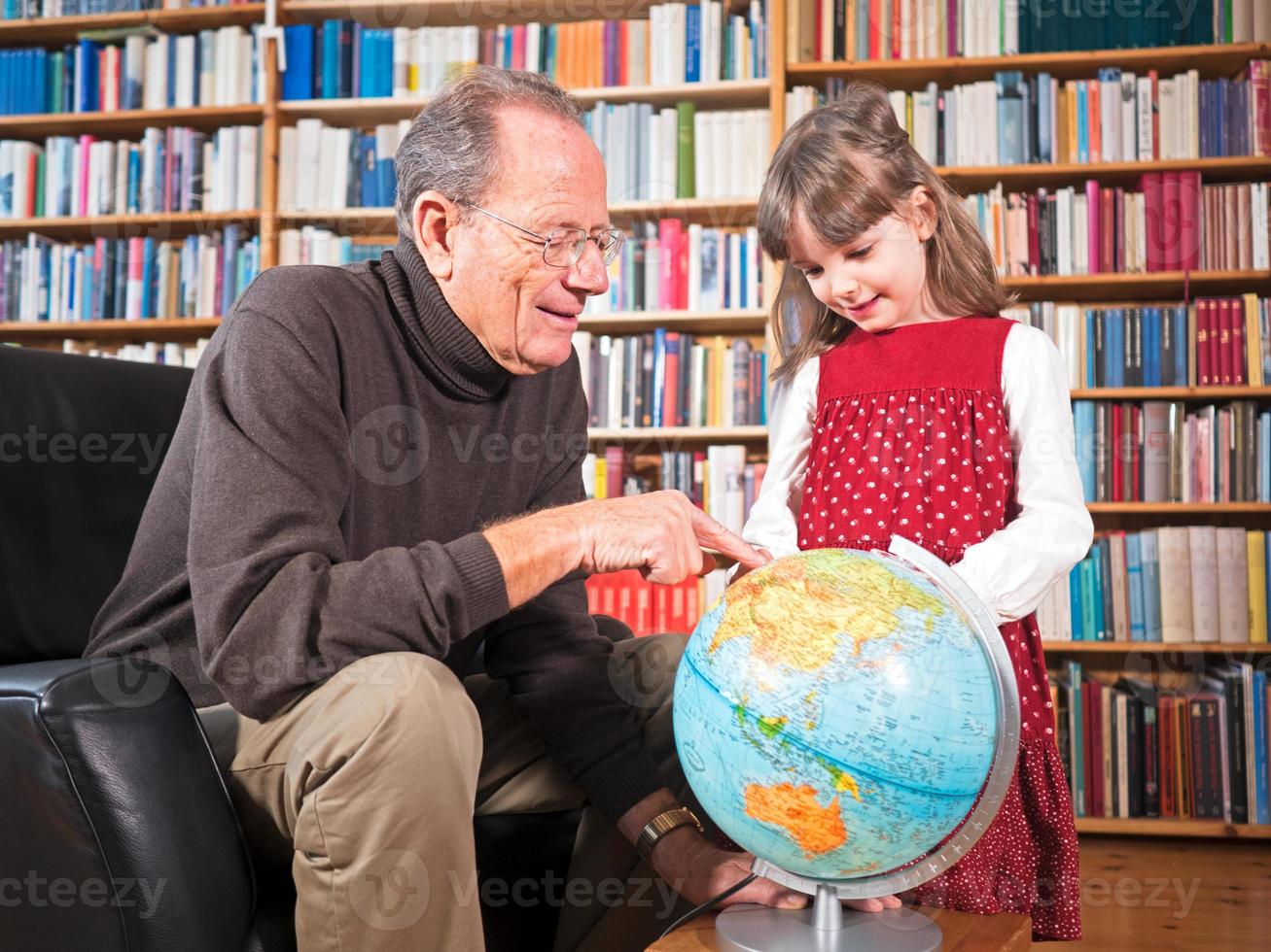 äldre och barnbarn tittar på ett jordklot foto