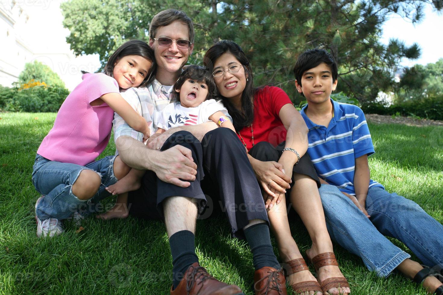 stor multiracial familj som sitter på gräsmattan foto