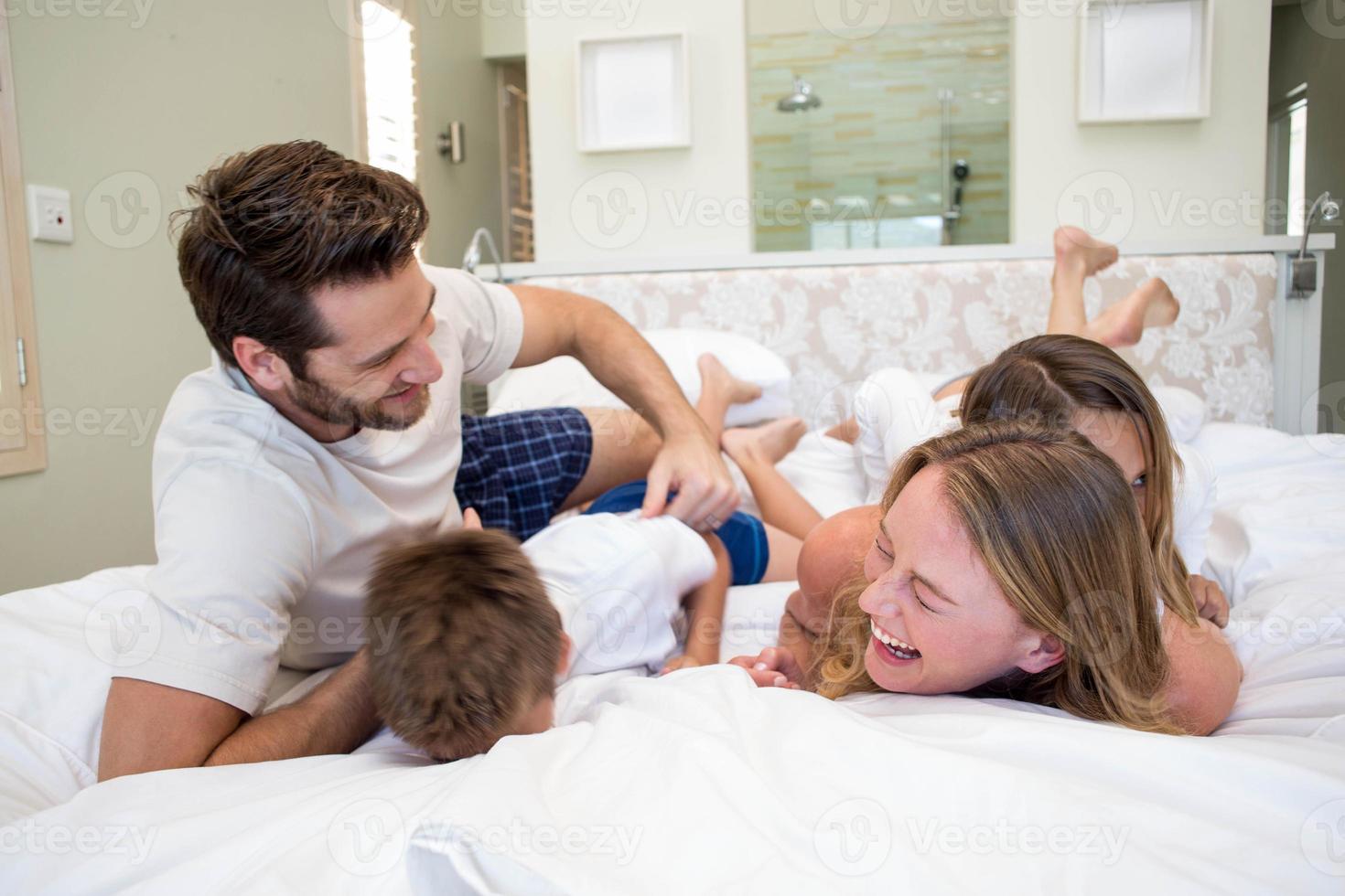 lycklig familj som leker på sängen foto