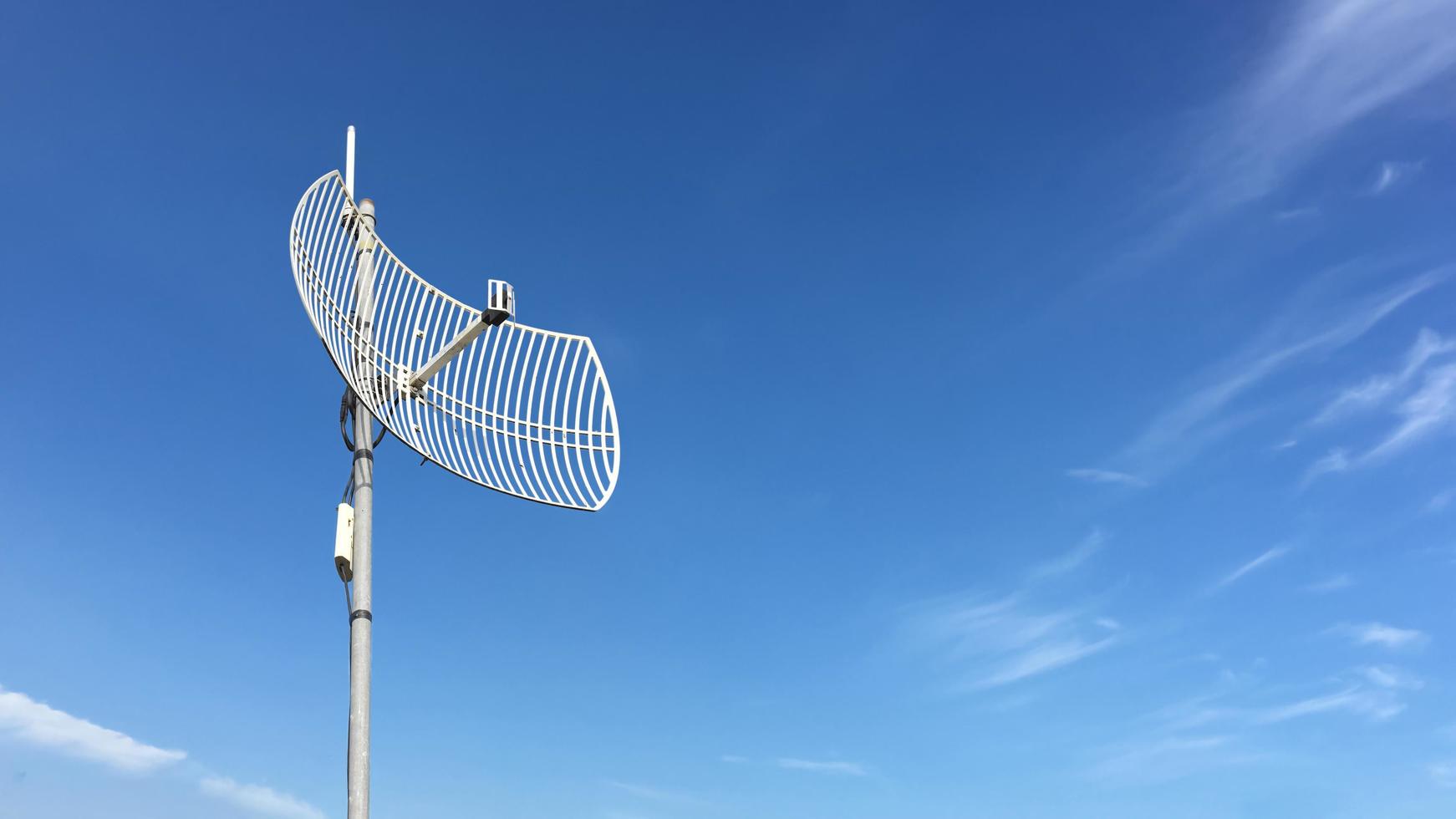 utomhus internet wifi-mottagare och repeaterantenn på taket av byggnaden med tydlig blåsky bakgrund. foto