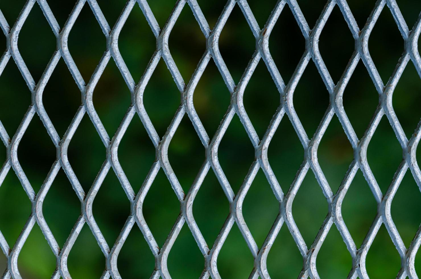 silver rutnät av metall staket med suddig grön färg bakgrund. foto