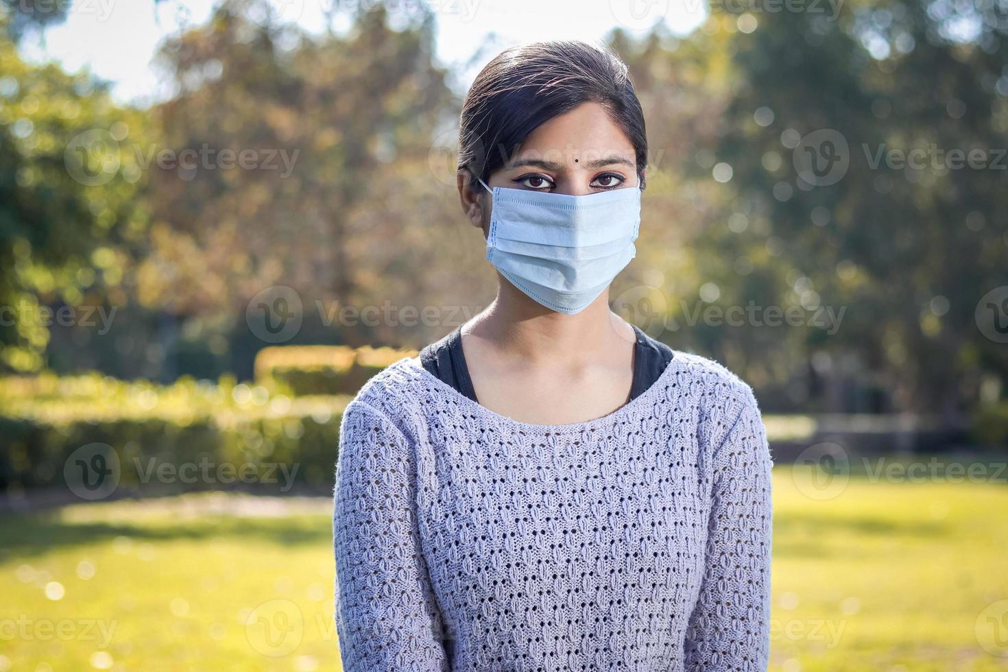 indisk tonåring tonårsflicka ung kvinna som bär en ansiktsmask utanför under coronaviruset covid-19 viruspandemin. foto