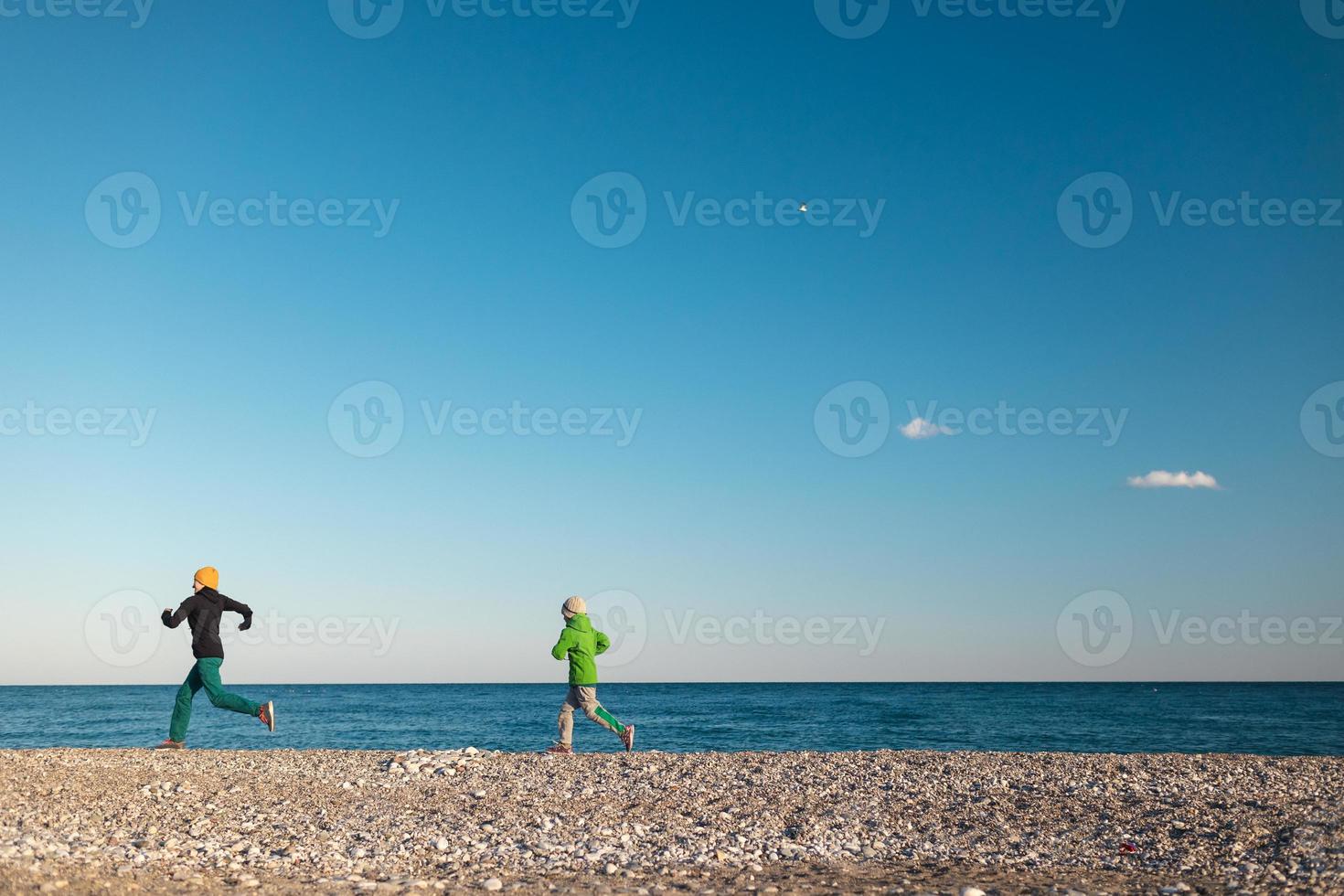 ett barn med sin mamma springer längs stranden foto