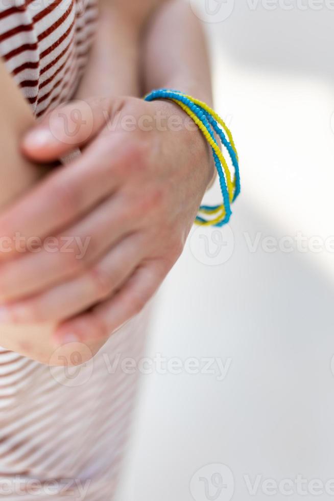 ett armband i den ukrainska flaggans färger på en kvinnas hand foto