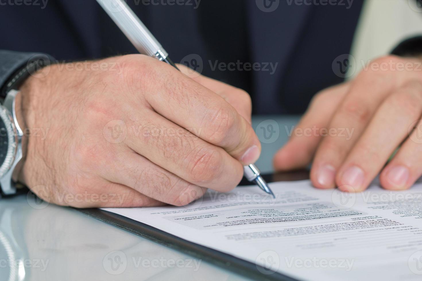 affärsman som sitter vid kontorsskrivbordet undertecknar ett kontrakt foto