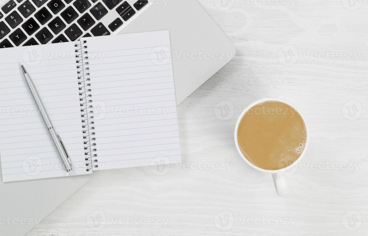 bärbar dator med kaffe och tomt anteckningsblock på vitt skrivbord foto