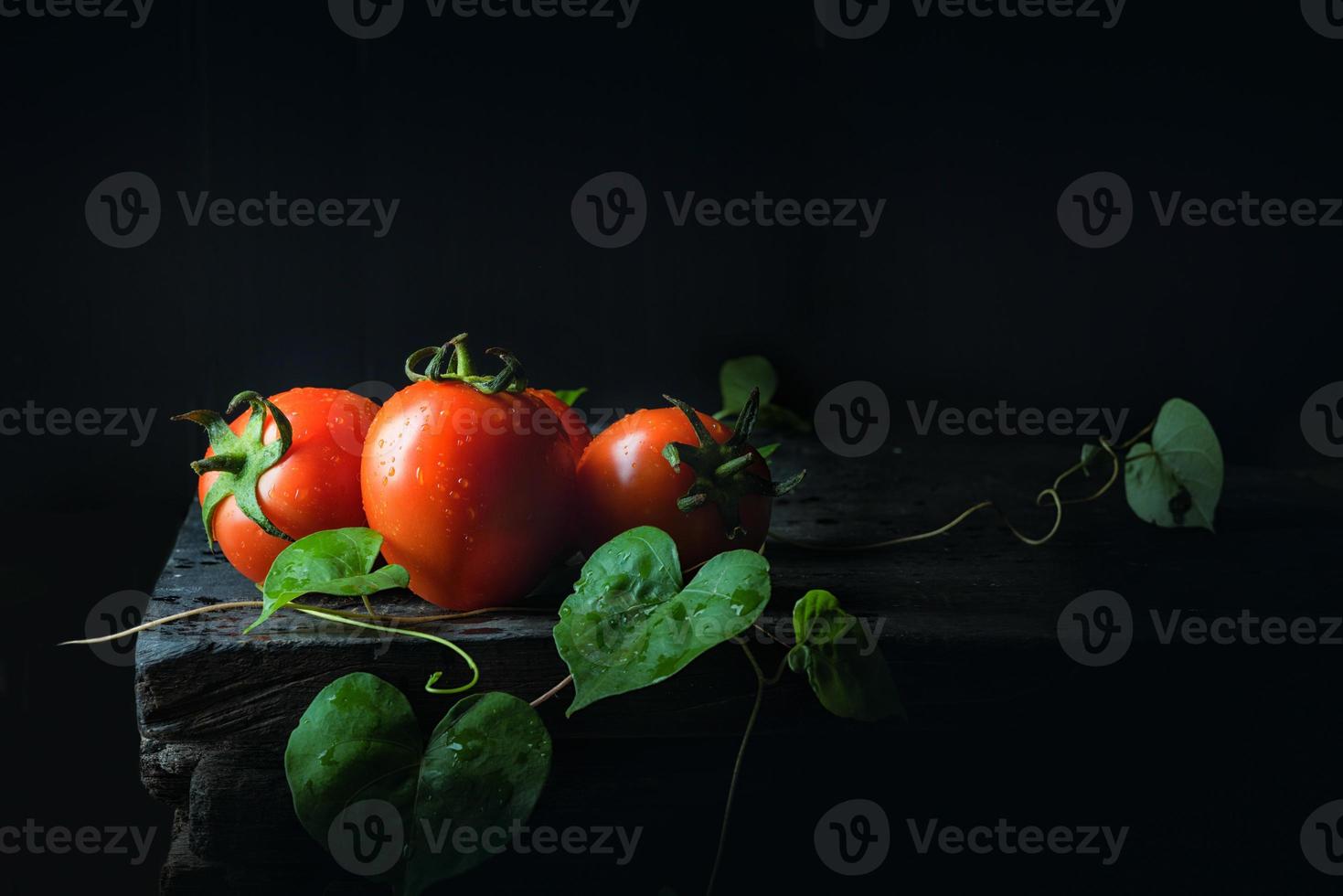tomat grönsak och grönt blad på gamla mörka trägolv antiksvart foto