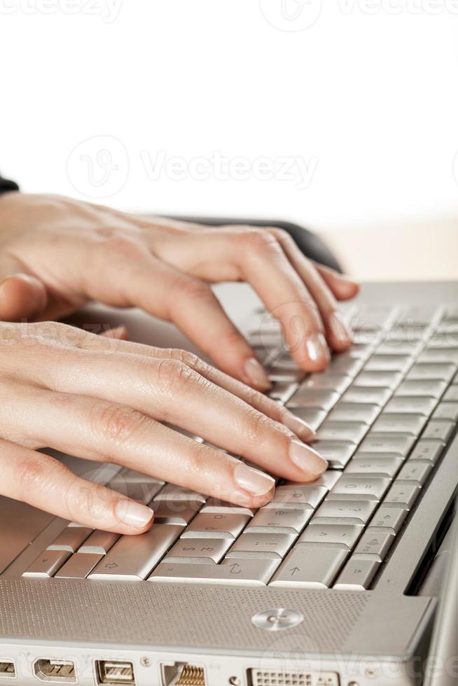 kvinnors fingrar som rör vid tangentbordet på den bärbara datorn foto