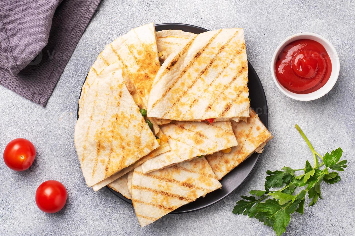 trekantiga skivor av en mexikansk quesadilla med såsen. den traditionella rätten i Mexiko är tortillas fyllda med kött och grönsaker. foto