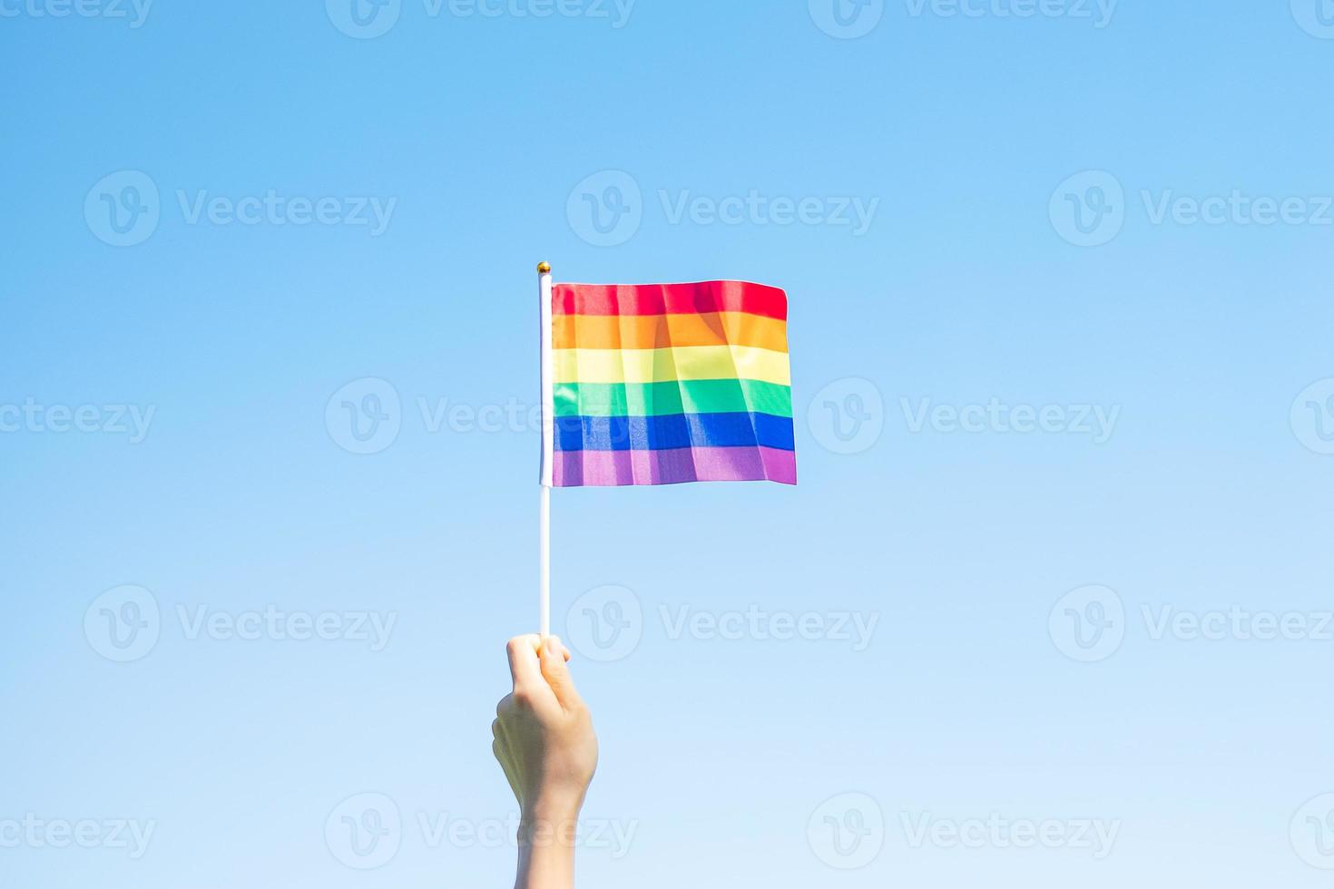 händer som visar lgbtq regnbågsflagga på naturbakgrund. stödja lesbiska, homosexuella, bisexuella, transpersoner och queer-gemenskaper och pride-månadskoncept foto