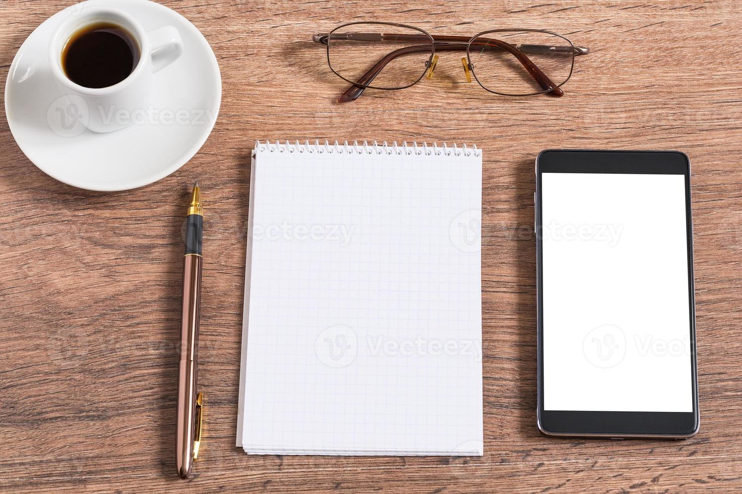 anteckningsbok med penna, smart telefon och kaffekopp foto