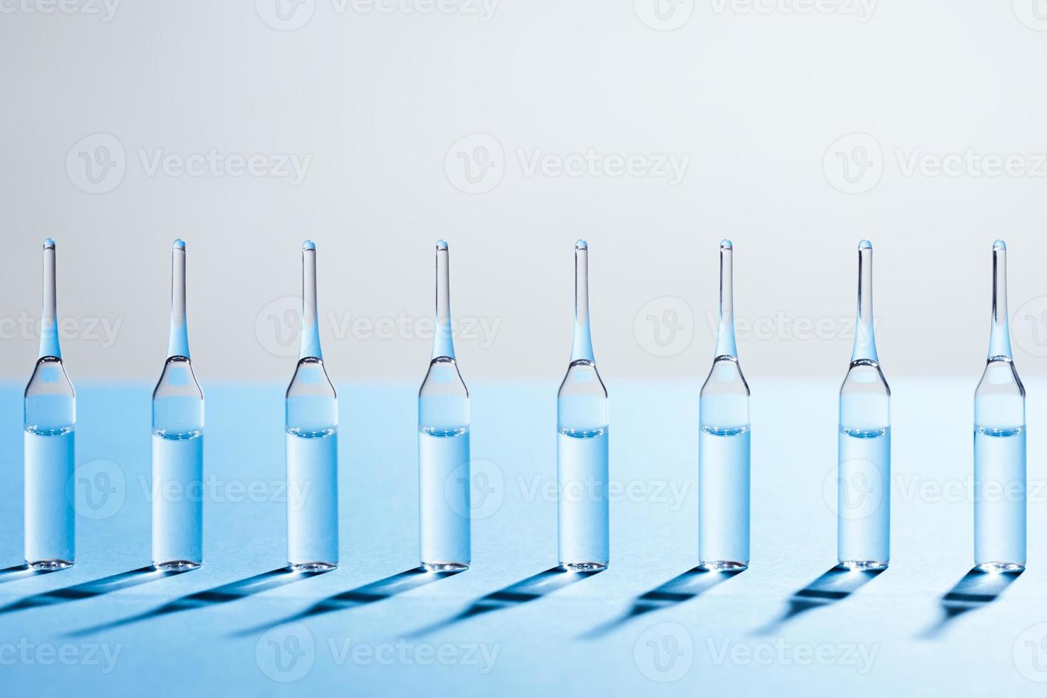 grupp av glasampuller står i rad på blå bakgrund. foto