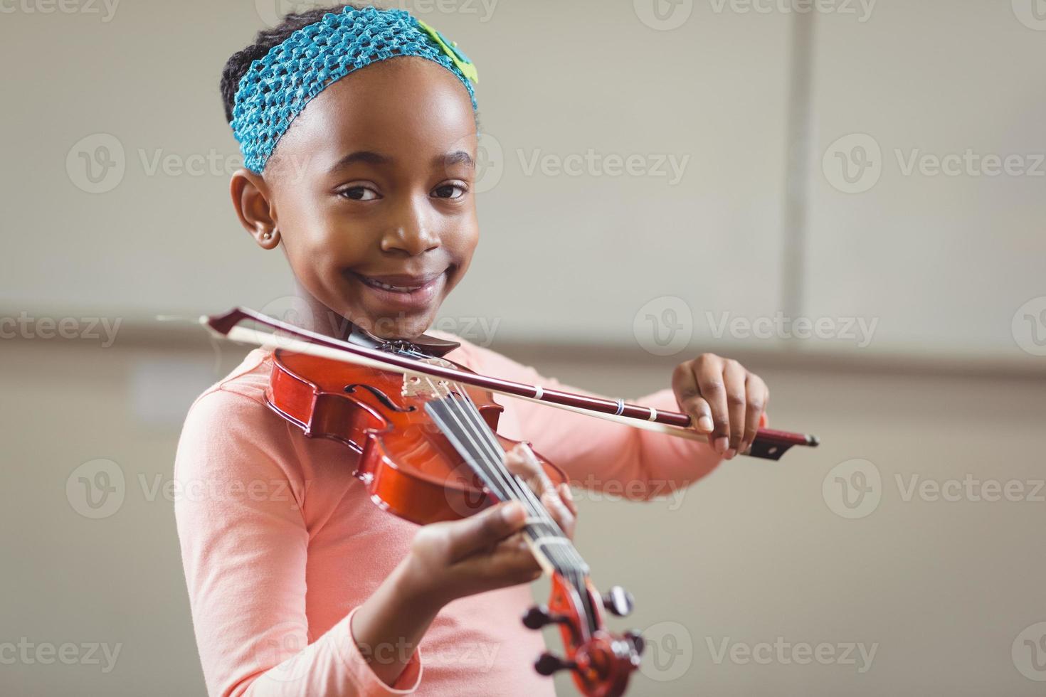 leende elev som spelar fiol i ett klassrum foto