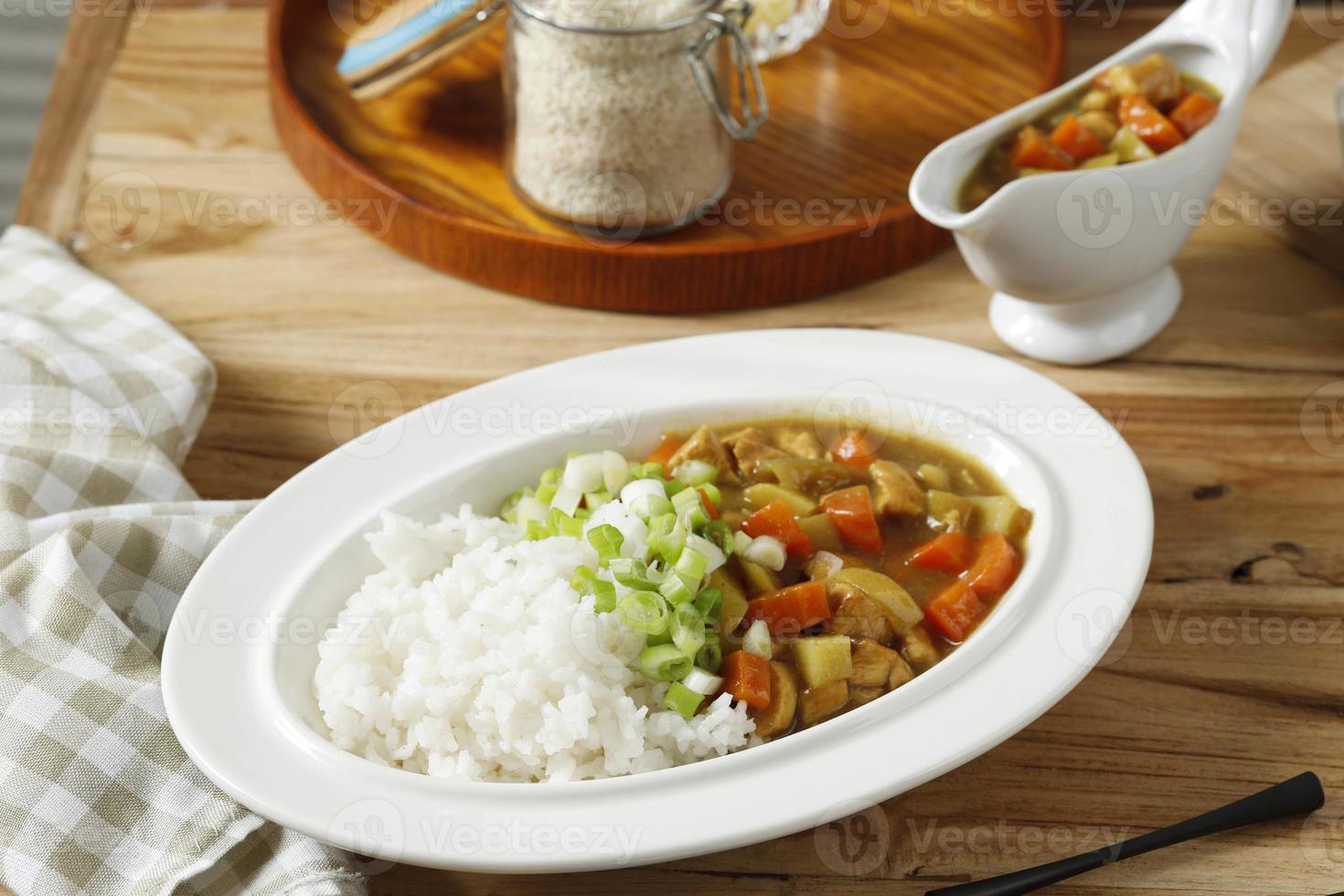 japanskt curryris med kött, morot och potatis. närbild på vit platta på träbord. foto